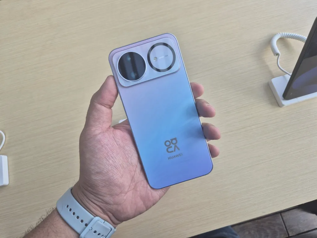 perangkat smarpthone berwarna biru dlaam genggaman tangan di hadapan meja coklat