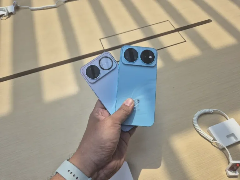 dua buah smarpthone berawarna biru dan ungu di genggaman tangan